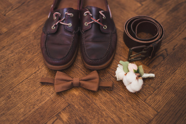 一套新郎领结，胸花，腰带和鞋子躺在木制背景。图片下载