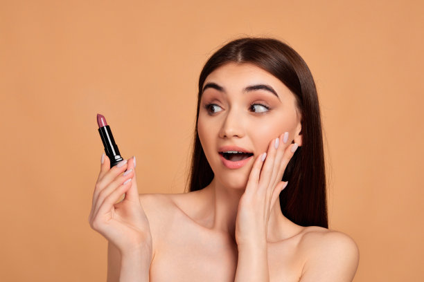 年轻快乐积极的女人拿着粉红色的口红图片下载