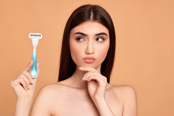 迷人的女孩手里拿着剃须刀，剃须刀刀片图片下载