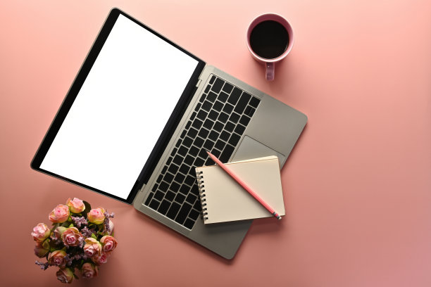 顶部视图甜的颜色平坦的一杯咖啡，笔记本，铅笔，笔记本电脑与一个空白的白色屏幕和鲜花在粉红色的背景，为商业和技术概念。图片下载