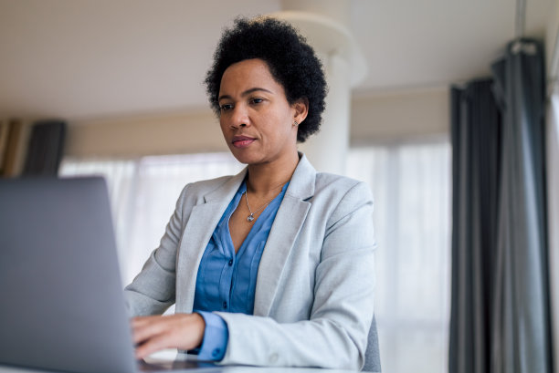 严肃的女性商业专业人士使用笔记本电脑在办公桌的特写图片下载