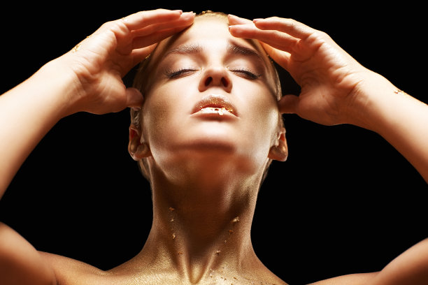 闭着眼睛，手靠近脸的女性。金色女孩在黑色背景图片下载