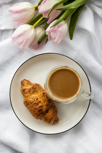 浪漫的早晨，一杯咖啡，床上放一个羊角面包，俯视图。图片下载