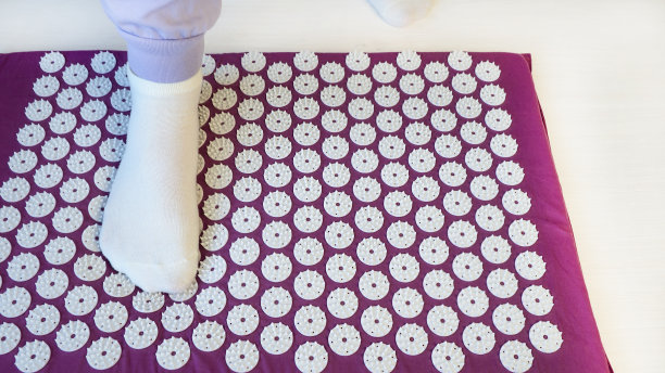 针灸按摩垫配枕头。把女孩的腿放在按摩垫上，替代医学的概念。针灸按摩垫配枕头。图片下载