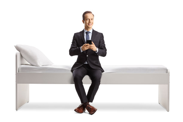 商人坐在床上用智能手机图片下载