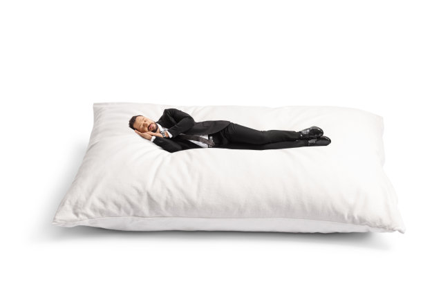 西装领带的商人睡在又大又软的枕头上图片下载