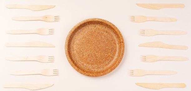 一次性餐具，放在压过的纸盘上，背景。由竹木和纸制成的环保一次性餐具，包括勺子、叉子、刀、竹碗等。副本的空间。图片下载