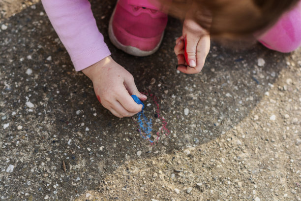 小孩在院子里画白色粉笔的特写图片下载