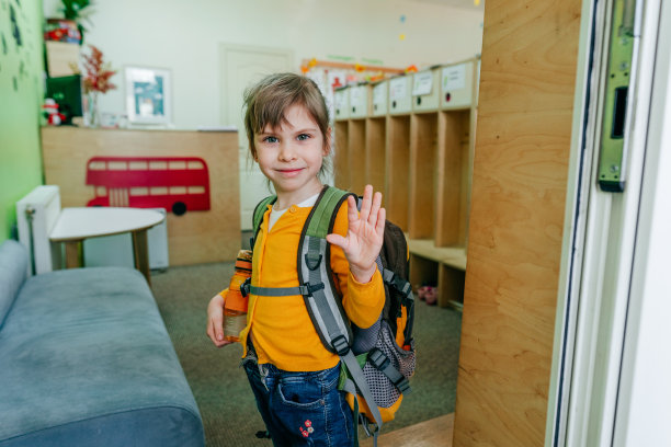 快乐的小女孩背着书包站在学校门口图片下载