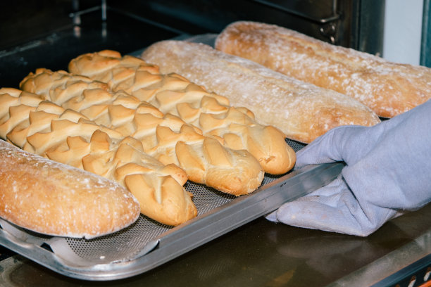 面包师戴着手套从烤箱里取出面包图片下载