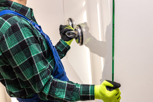 一个玻璃工人手里拿着一块厚玻璃，手里拿着一个特殊的吸盘图片下载