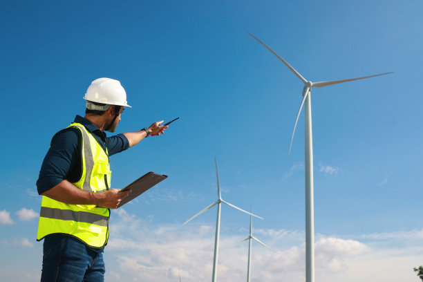 智能工程师佩戴安全防护装备，通过对讲机与团队沟通，在风电场户外工作，工程师在风电场现场工作图片下载