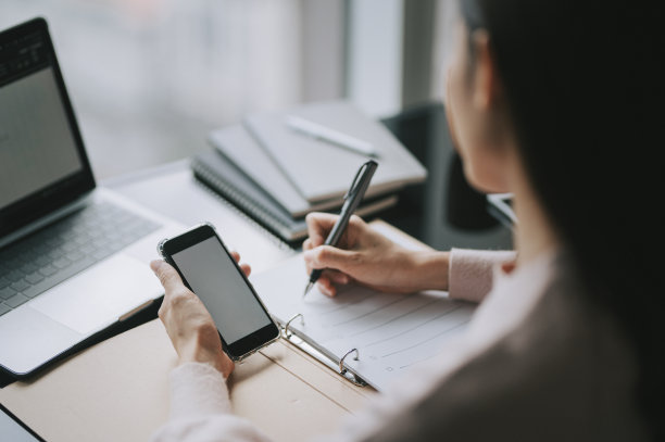 亚洲华裔女性在家里写作和使用智能手机学习工作图片下载