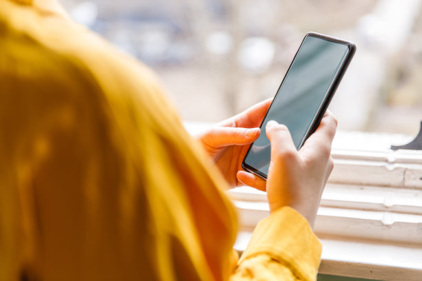 站在窗边用智能手机的女人图片下载