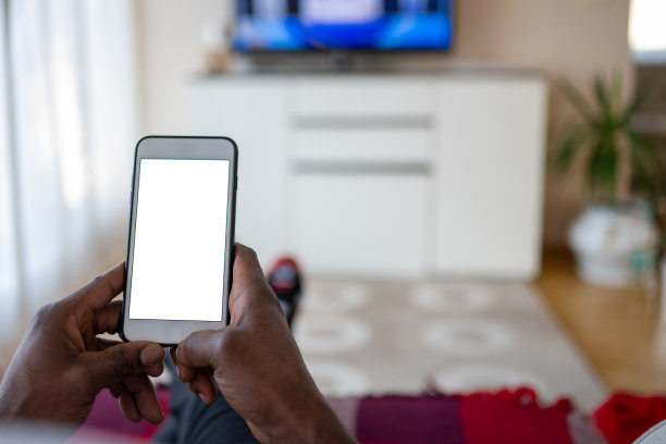 黑人一边看电视一边用智能手机图片下载