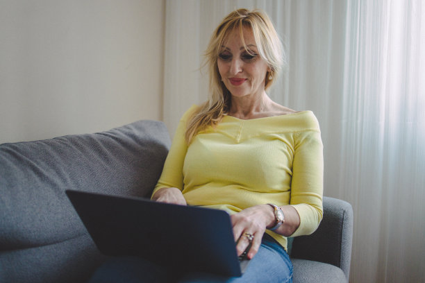 一个成熟的女人用她的笔记本电脑看视频图片下载