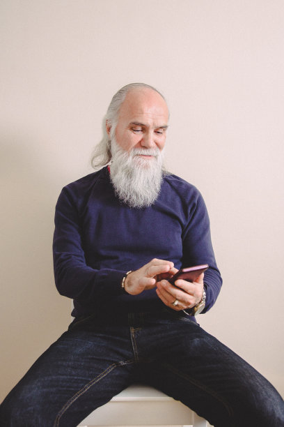 一个留着胡子的成熟男人用手机看视频图片下载