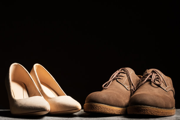 绒面革女人和男人的鞋子站在一个黑色背景并排图片下载