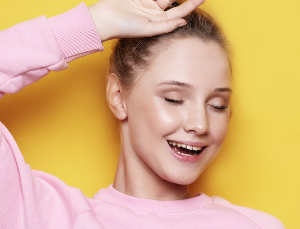 年轻的金发女人闭着眼睛，在黄色的背景图片下载