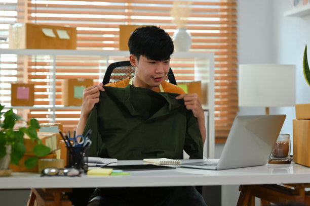 一名亚洲男子的肖像，电子商务员工坐在办公室里的包裹在背景上展示衬衫的流媒体，中小企业业务，电子商务和快递业务。图片下载