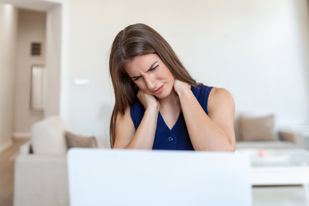 感到疲惫：沮丧的年轻女性在工作场所按摩颈部图片下载