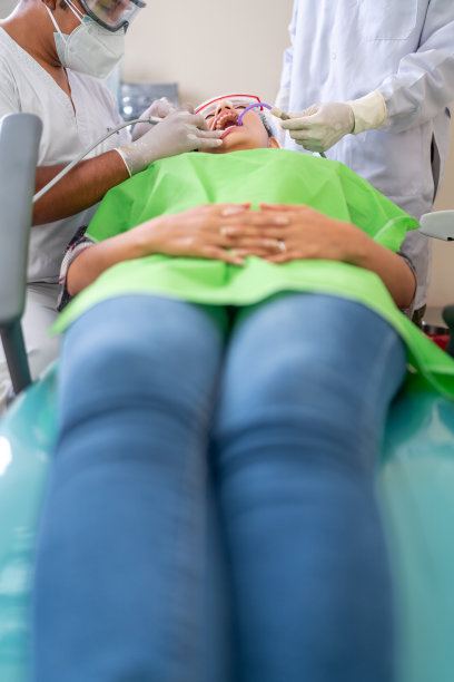 一名妇女躺在担架上，牙医正在清洁她的口腔图片下载