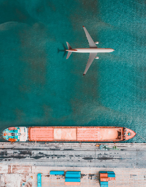在货轮上方飞行的飞机。图片下载