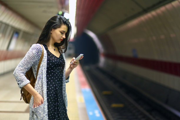年轻女人看电话，乘客在车站等地铁，旅游女人在城市旅行图片下载