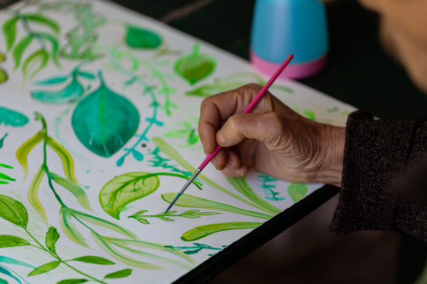 一位老人用画笔画的树叶装饰品图片下载