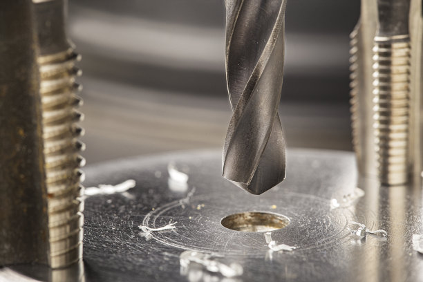 金属钻头在带刨花的工业钻床上的铝坯上打孔。金属加工行业。多刀和立铣刀。图片下载