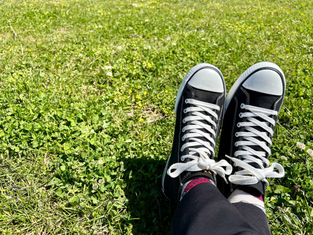 黑色和白色运动鞋在草地上与复制空间交叉的脚图片下载