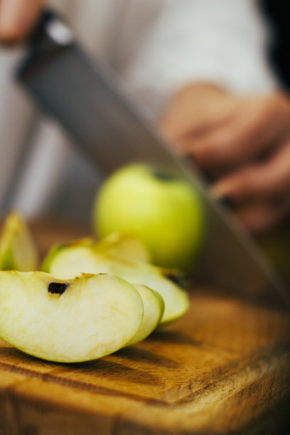 在砧板上把青苹果切成片。准备健康的饭菜。素食食物。股票的照片。图片下载