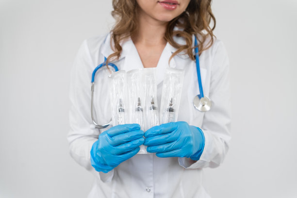 一个穿着浴衣拿着听诊器的医生的肖像。这个女孩手里拿着一支医用注射器。图片下载