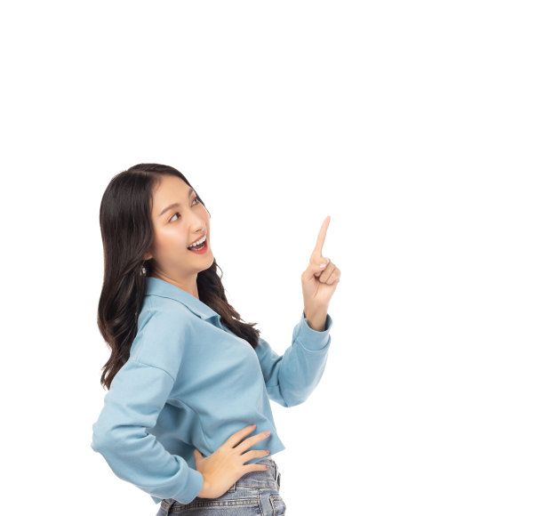 漂亮年轻的亚洲女人指着拷贝空间，看着微笑的脸和快乐的漂亮女孩像一个满意的产品，用于广告与孤立的白色背景图片下载