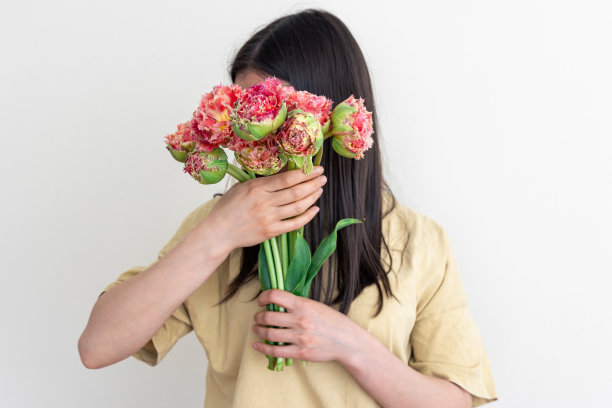 一个年轻的女人拿着一束白色背景的花。图片下载