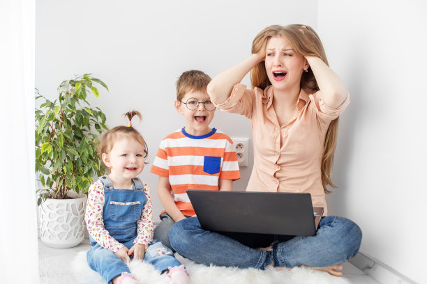忙碌的女人一边工作一边照顾两个孩子。巨大的压力。图片下载