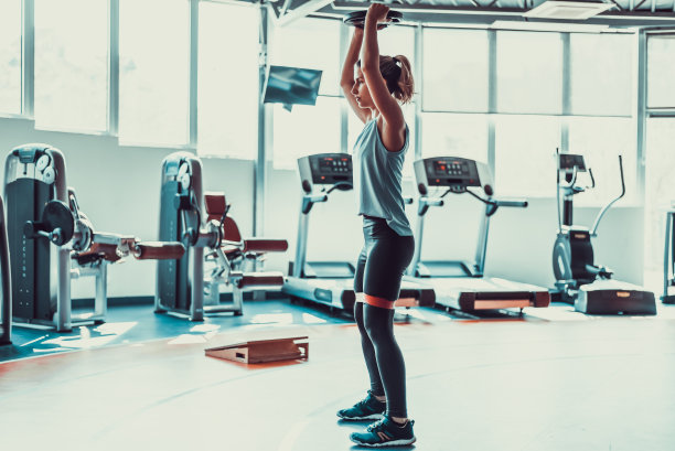 有魅力的女人用橡胶带和重量在健身房锻炼，库存照片图片下载