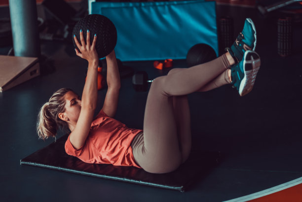 迷人的女人工作，举重球在健身房，股票照片图片下载