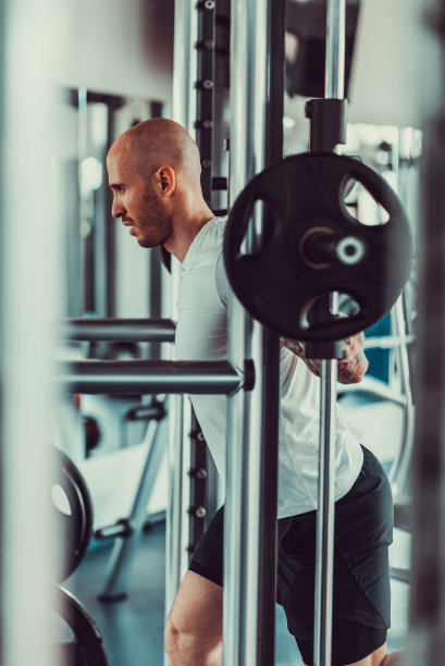 帅哥在健身房的健身机上举重，股票照片图片下载