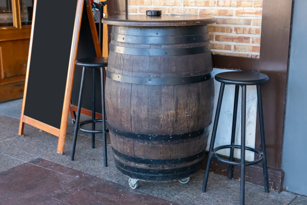 用作桌子的大木桶和空荡荡的黑色餐厅菜单广告牌放在餐厅外面图片下载