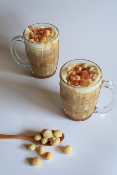 咖啡与夏威夷坚果和焦糖甜点休息在白色的背景。图片下载