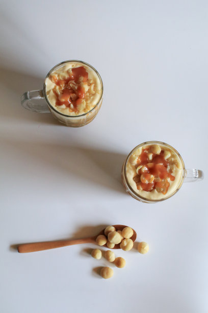 咖啡与夏威夷坚果和焦糖甜点休息在白色的背景。图片下载