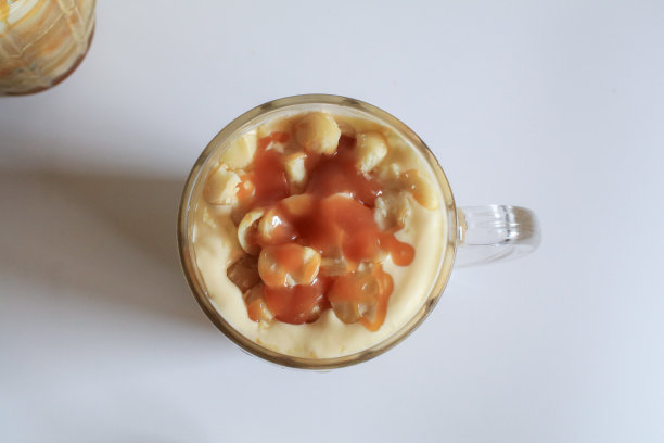 咖啡与夏威夷坚果和焦糖甜点休息在白色的背景。图片下载