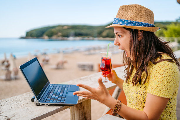 在海滩上使用笔记本电脑的年轻女子Café图片下载