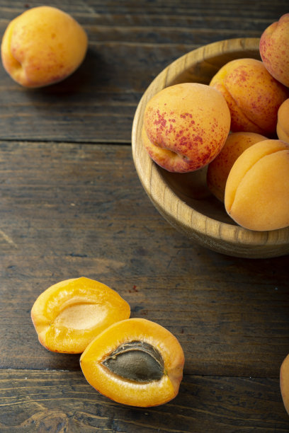 木盘子里的新鲜杏。水果散落在一张木桌上。图片下载