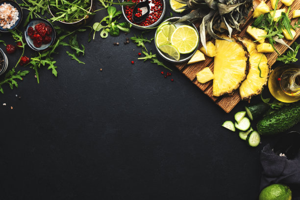 健康饮食的食品布局和饮食营养理念。菠萝，蔬菜，水果，绿色蔬菜和其他原料的沙拉准备在黑色的桌子背景，横幅图片下载