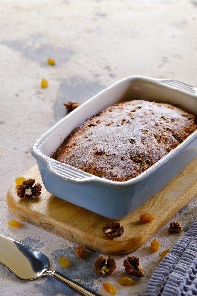一个美味馥郁的纸杯蛋糕，用葡萄干、梅干和坚果制成的长方形陶瓷蛋糕，从烤箱中取出，背景明亮图片下载