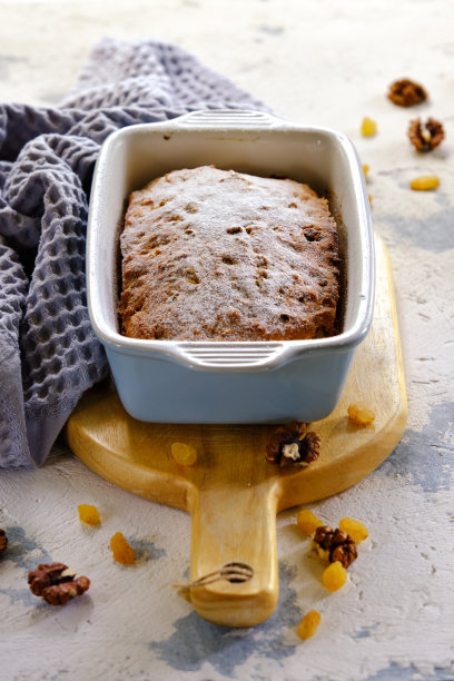 一个美味馥郁的纸杯蛋糕，用葡萄干、梅干和坚果制成的长方形陶瓷蛋糕，从烤箱中取出，背景明亮图片下载