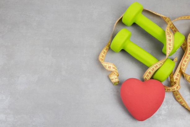 哑铃，灰色纹理背景上的卷尺。健身、运动营养图片下载