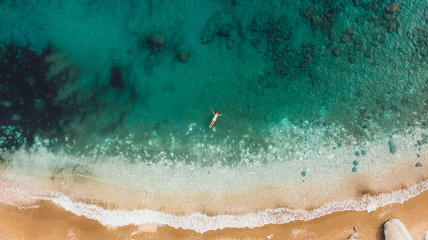 一名女子漂浮在水晶蓝色的海洋与珊瑚礁在土耳其的鸟瞰图图片下载